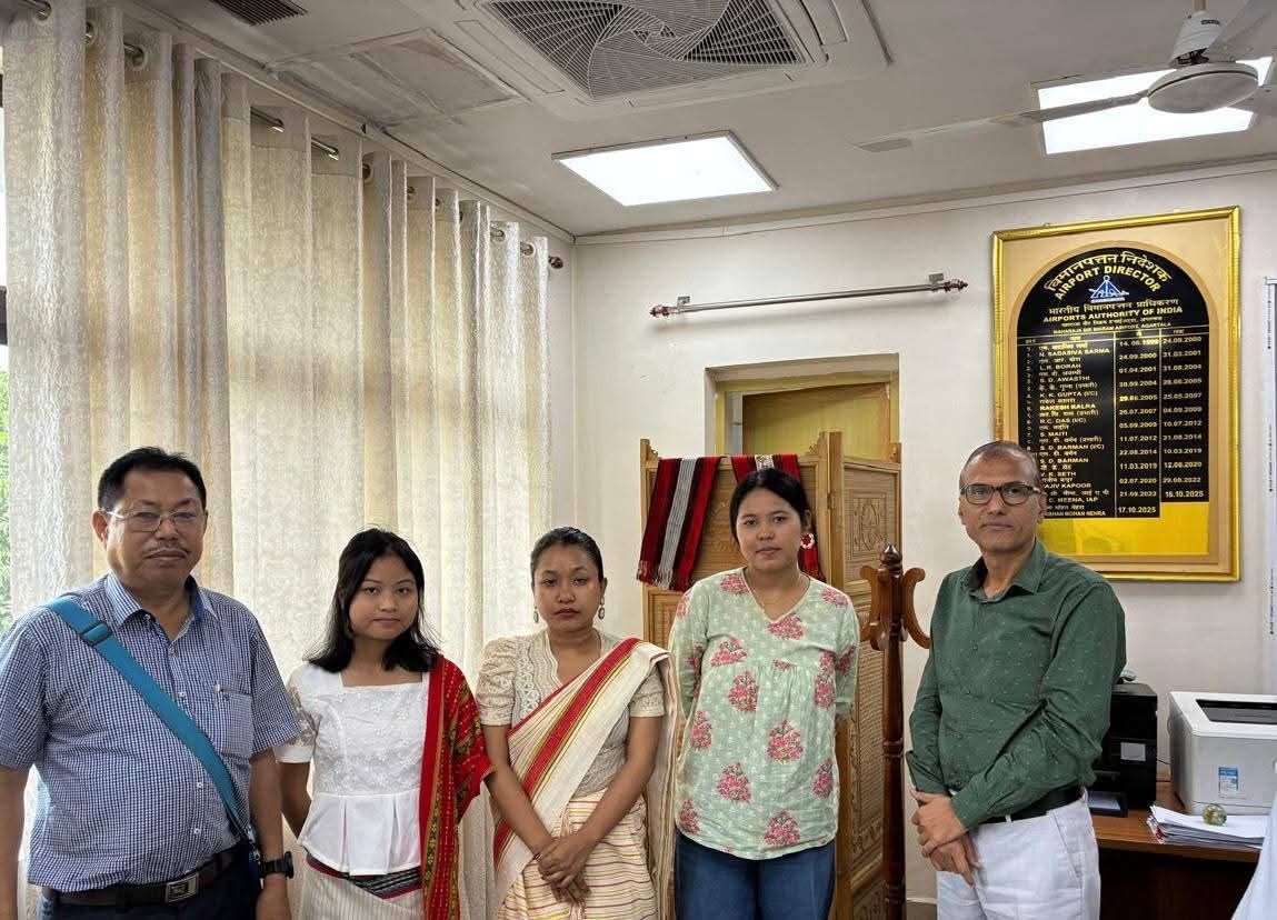 Members gathered in an office beside a wall plaque.
